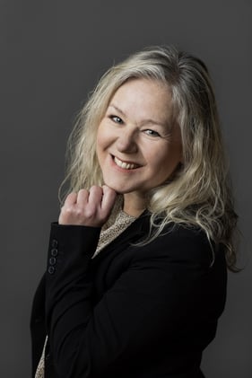 Portret van Mirjam Steijnis, 56-jarige finance consultant bij BAS, die lachend in een lichte kantooromgeving staat. In de begeleidende tekst vertelt zij over haar overstap van een leidinggevende rol in de zorg naar consultancy, haar huidige opdracht bij Stichting DOCK en waarom de cultuur bij BAS zo goed bij haar past.